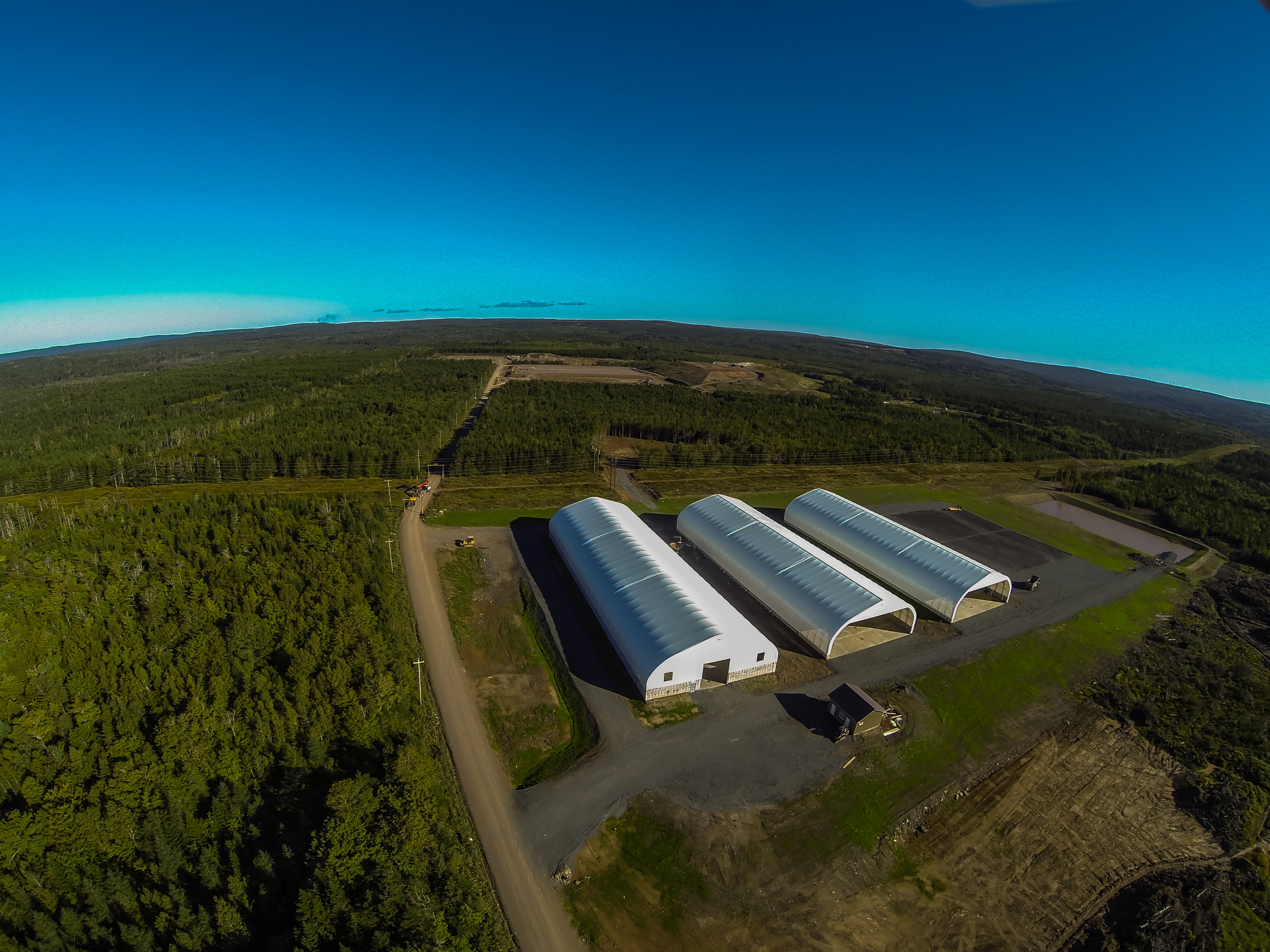 Aerial view of three fabric buildings at a facility surrounded by forest