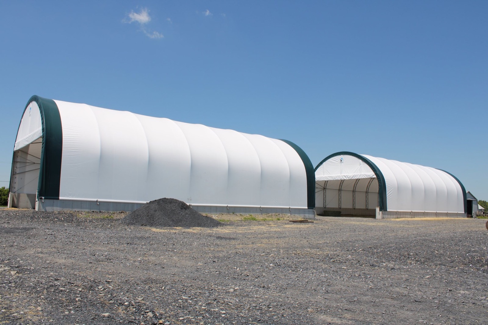 Two fabric buildings for hay and grain storage with open-end loader access
